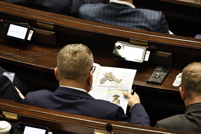W  czasie obrad Sejmu poseł przeglądał katalog z bronią