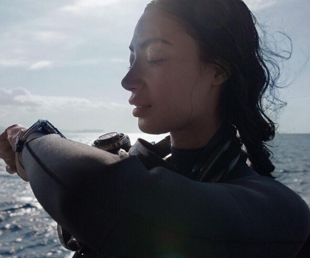 Kobieta w stroju do nurkowania spoglądająca na smartwatch Huawei Ultimate 2 na nadgarstku, na tle otwartego morza. Zegarek jest elementem promocji walentynkowej Huawei, o której przeczytasz więcej na Super Biznes.