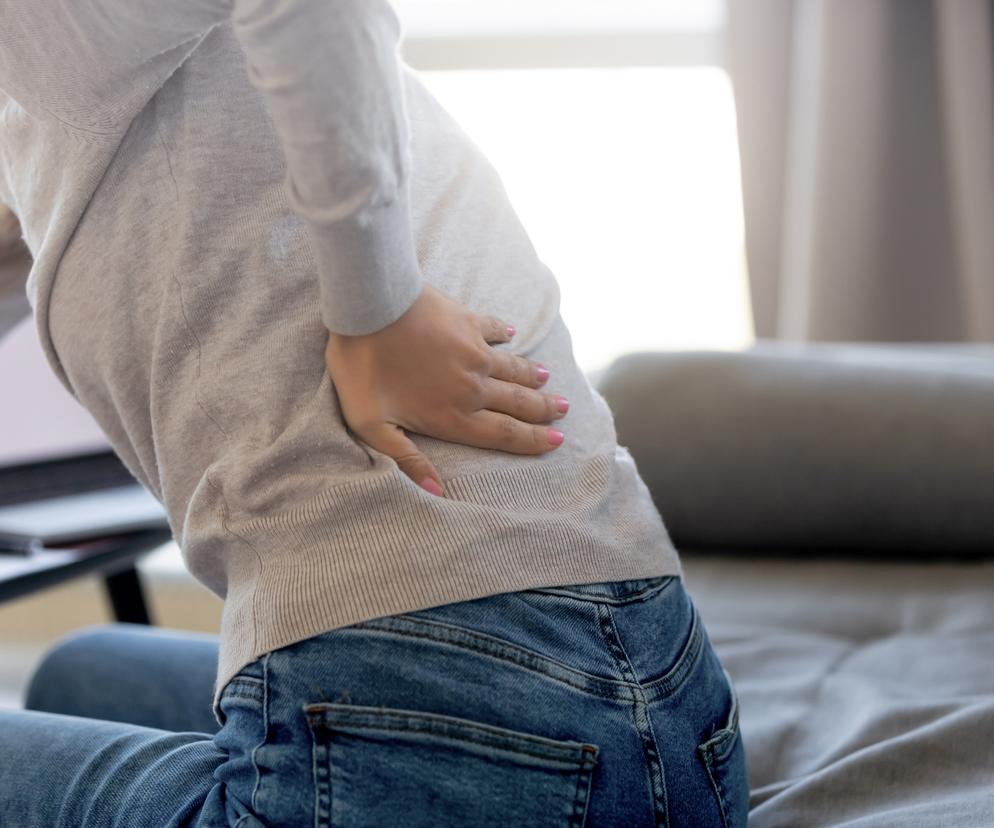 Kobieta trzyma się za plecy 