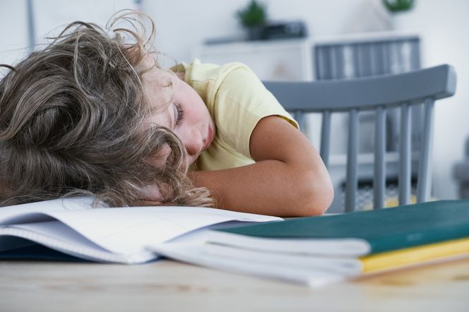 Zmęczone dziecko opiera głowę o stół