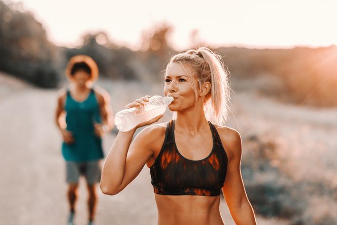 Kobieta pije wodę podczas biegania