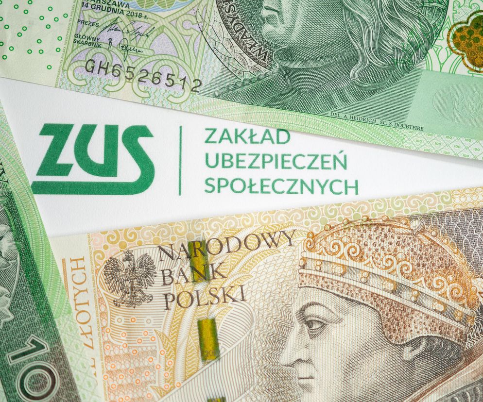 Widok z góry na pieniądze (banknoty) leżące na białym tle, na którym widnieje zielone logo Zakładu Ubezpieczeń Społecznych, symbolizujące świadczenia, w tym rentę alkoholową. Więcej o zasadach przyznawania świadczeń z ZUS przeczytasz na Poradnik Zdrowie.