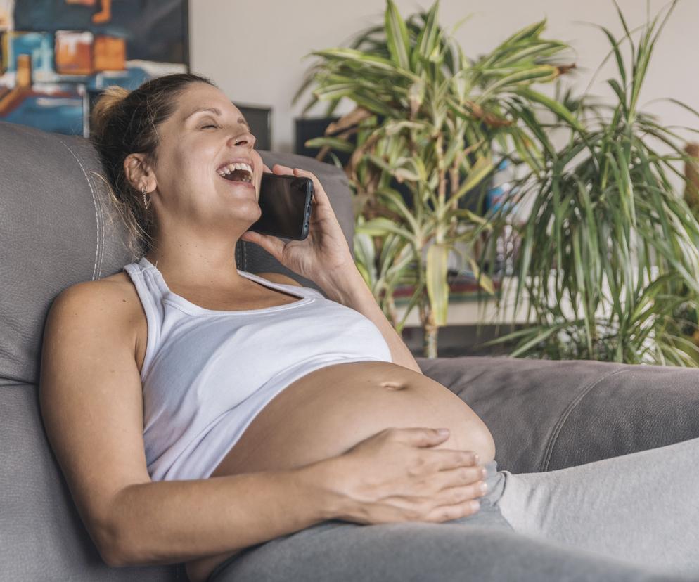 Kobieta w ciąży rozmawia przez telefon i się śmieje