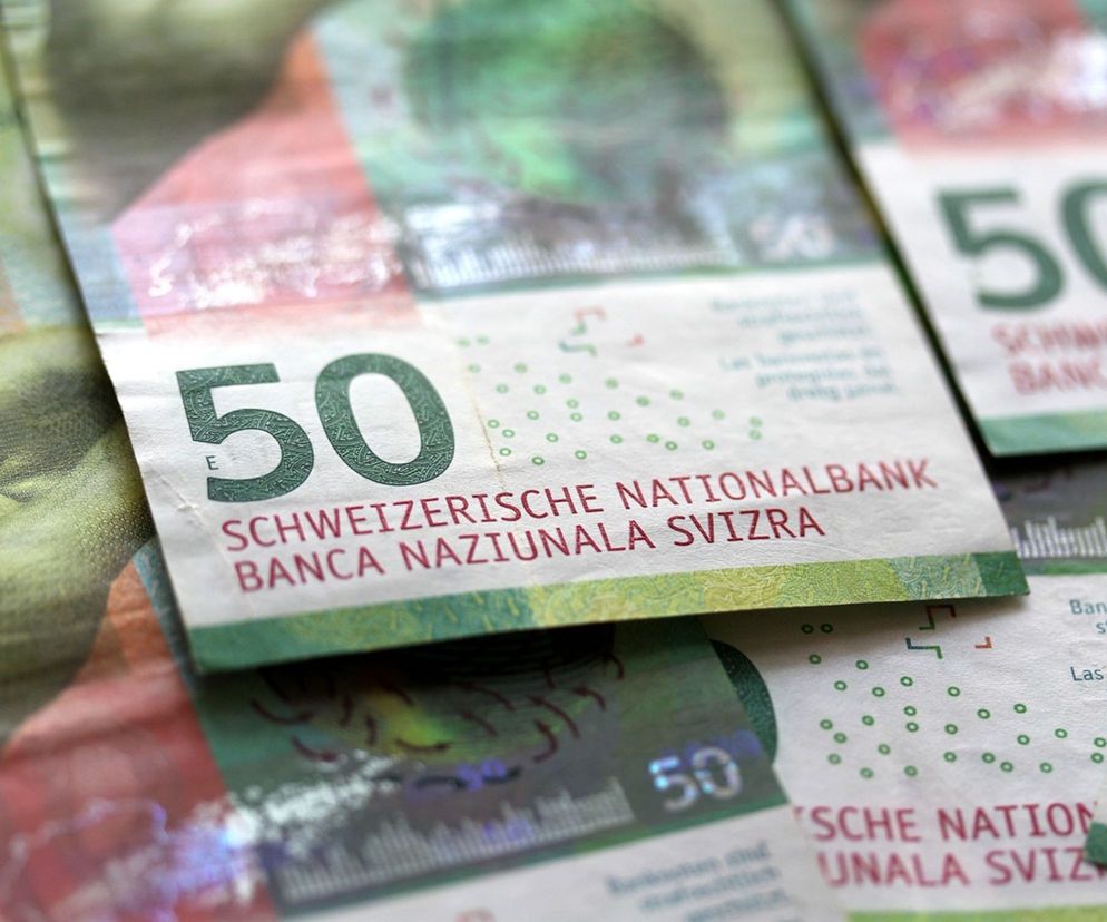 Rozłożone banknoty 50 franków szwajcarskich, dominujące kolory to zielony i czerwony. Symbol waluty, której kurs wobec złotego rośnie, co jest kluczowe dla bieżących analiz ekonomicznych. Więcej o aktualnych kursach walut przeczytasz na portalu Super Biznes, gdzie znajdziesz szczegółowe informacje o notowaniach CHF/PLN.