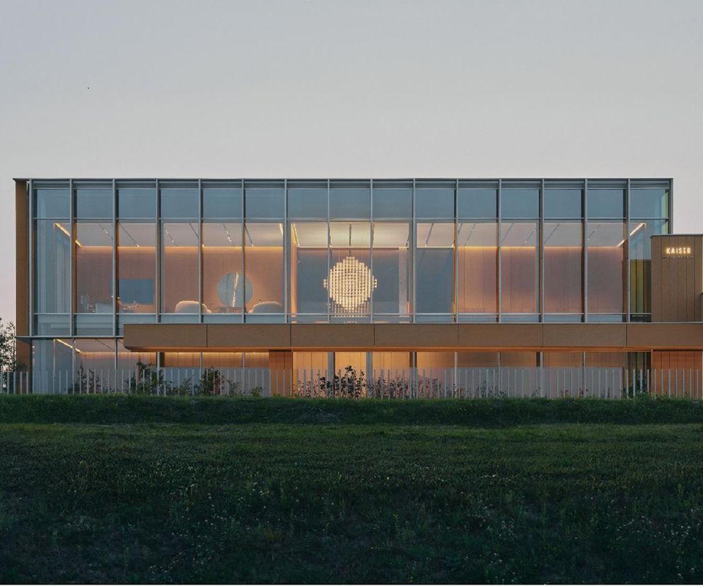 Nowoczesny obiekt biurowy Pracownia Omni Kaiser Patisserie w Słupsku autorstwa ACOS + Studio Widoki, z fasadą szklaną i ochrowymi elementami, otoczony zielenią, harmonijnie współgra z otoczeniem. Projekt zrealizowany w Słupsku to przykład architektury, o której można przeczytać na Architektura Murator Plus.