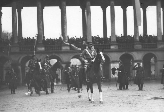 Józef Piłsudski na koniu przyjmuje defiladę wojskową w Warszawie (w tle kolumnada Pałacu Saskiego)