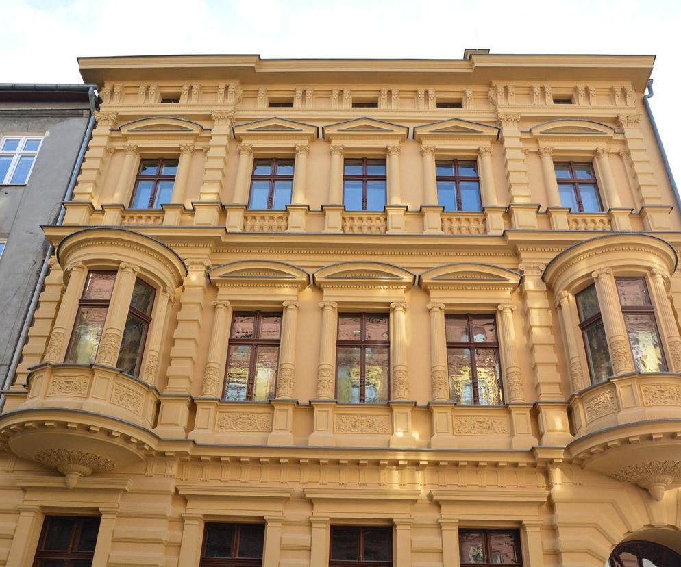 Odrestaurowana kamienica Hilarego Majewskiego przy ul. Włókienniczej 11 w Łodzi, z elewacją w kolorze żółtym, bogato zdobioną detalami architektonicznymi i wykuszami. Przebudowa i zmiana sposobu użytkowania obiektu to temat, o którym przeczytasz na Architektura Murator Plus.