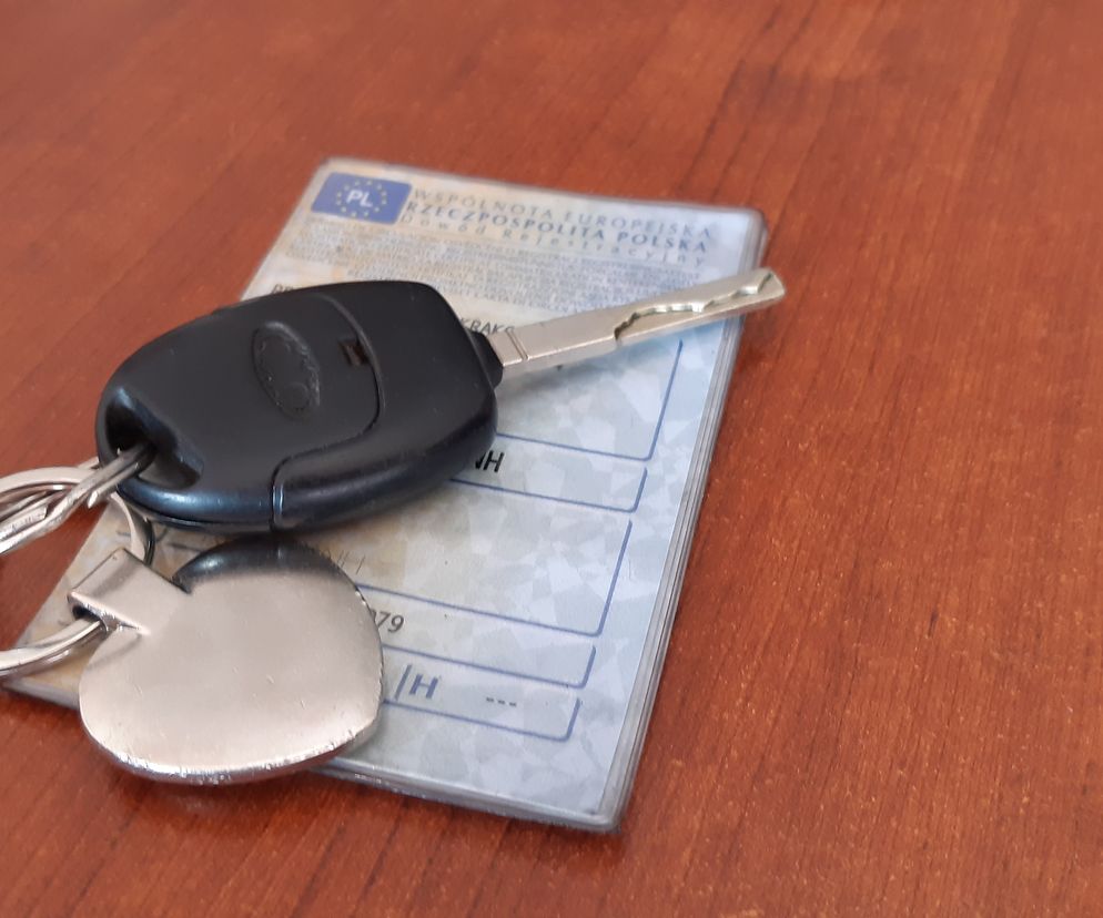 Kluczyk samochodowy z brelokiem leżący na dowodzie rejestracyjnym pojazdu na drewnianym blacie, symbolizujący zmiany dotyczące cyfryzacji dokumentów. Koniec papierowych dowodów rejestracyjnych to ważny temat, o którym przeczytasz na Super Biznes.