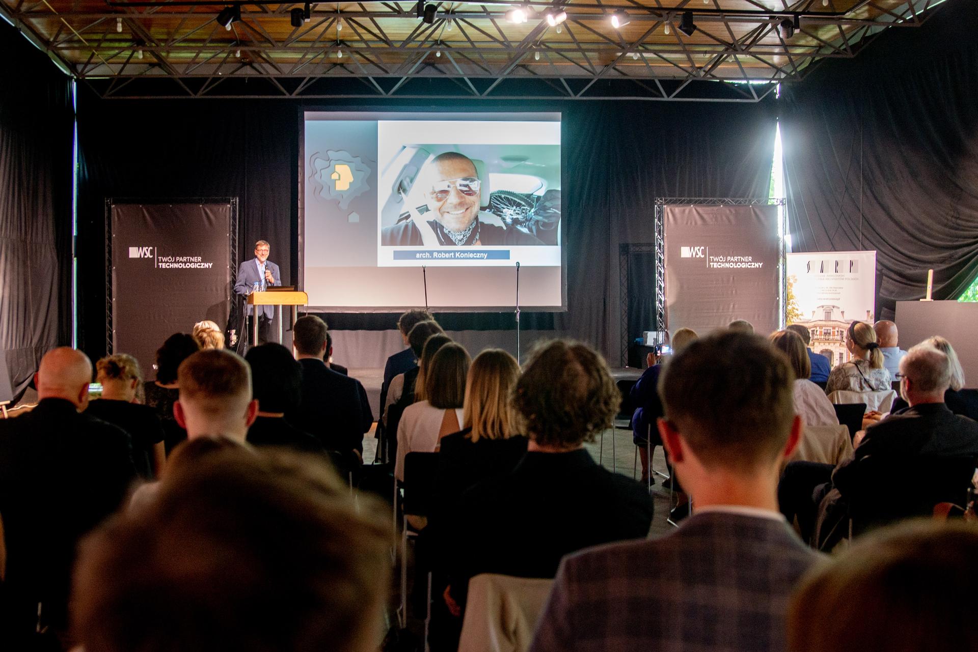 Członek jury Robert Konieczny pozdrawia z ekranu uczestników konkursu