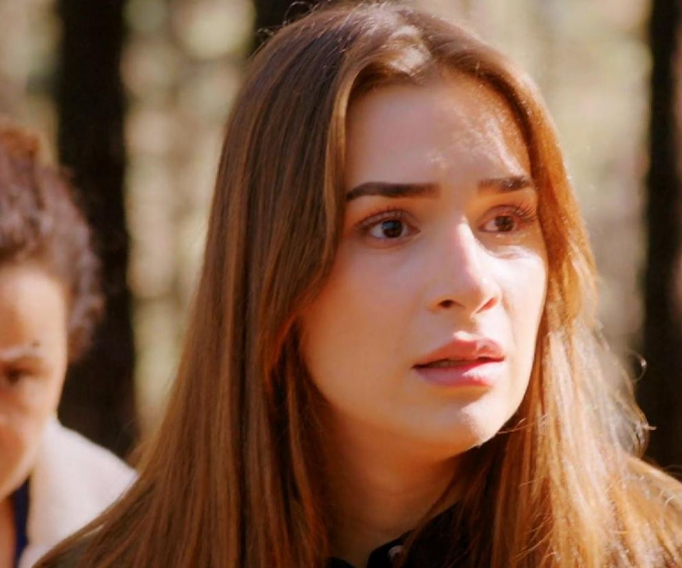 Sila z serialu Miłość i nadzieja, młoda kobieta z długimi brązowymi włosami i wyrazistym makijażem, spogląda w przód z zaniepokojeniem. Za nią, w tle, widoczna jest Cavidan z pochmurną miną. Obie postacie są w lesie. Więcej o ich losach przeczytasz na Super Seriale.