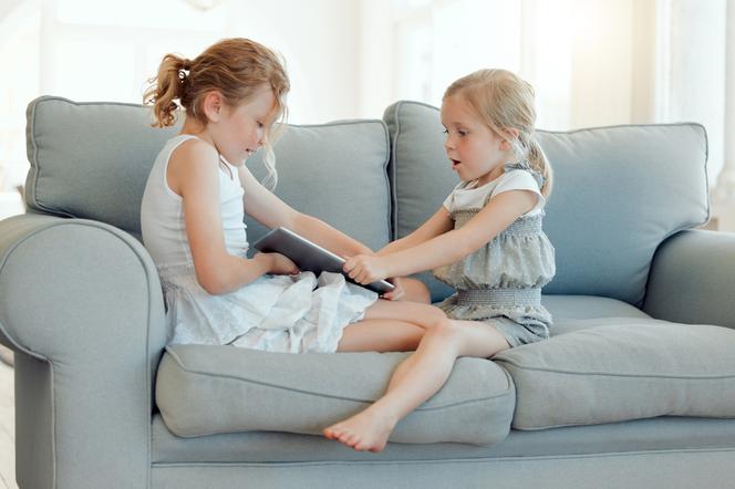 Dziewczynki na kanapie wyrywające sobie książkę