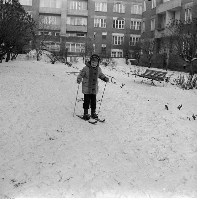 Dziecko na nartach biegowych na podwórku. W tle blok przy ul. Rakowieckiej 59/59A
