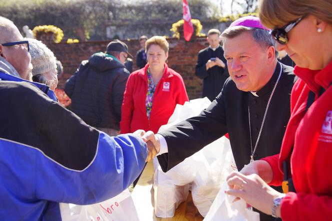 Arcybiskup Józef Kupny wręcza żywność mieszkańcom miasta