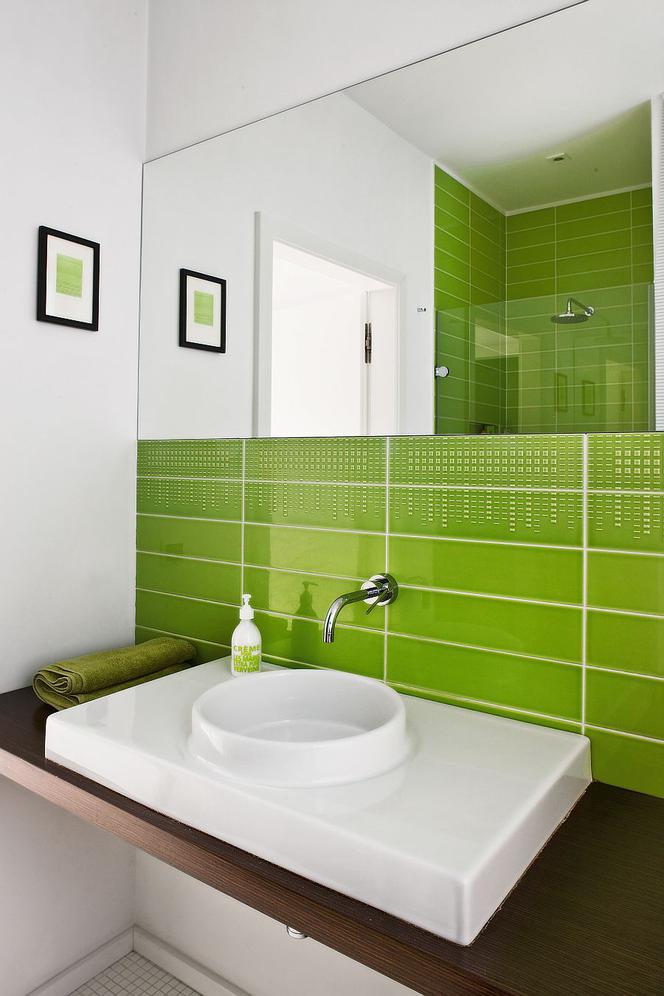 Zielona łazienka z płytkami nad umywalką