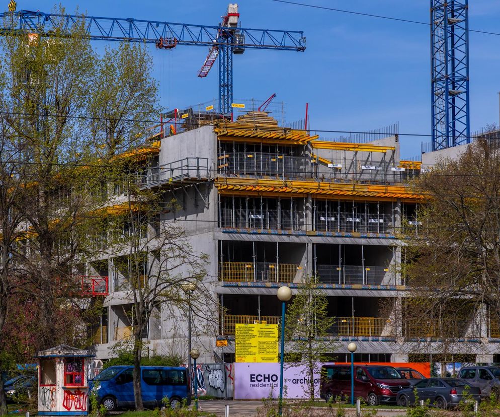 Budowa osiedla na warszawskim Mokotowie, gdzie widoczny jest betonowy szkielet budynku mieszkalnego z licznymi szalunkami i żurawiem. Obraz ilustruje trend rosnących cen mieszkań w stolicy, o czym można przeczytać na Super Biznes.
