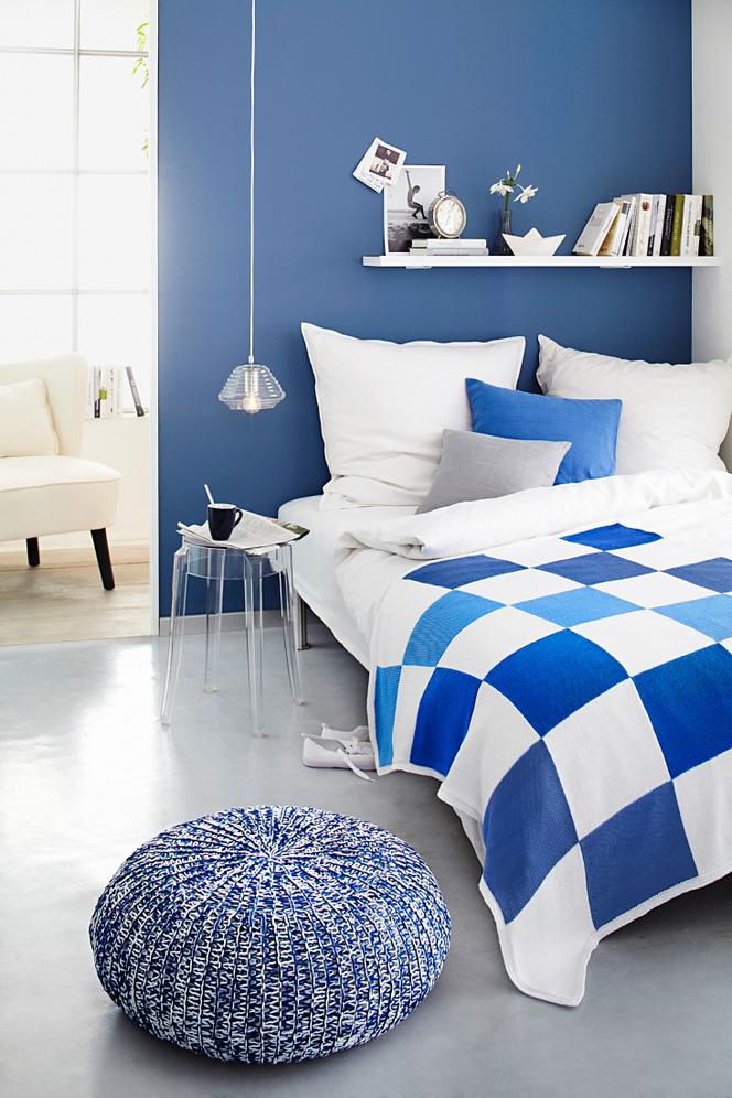 Niebieska ściana za łóżkiem w sypialni