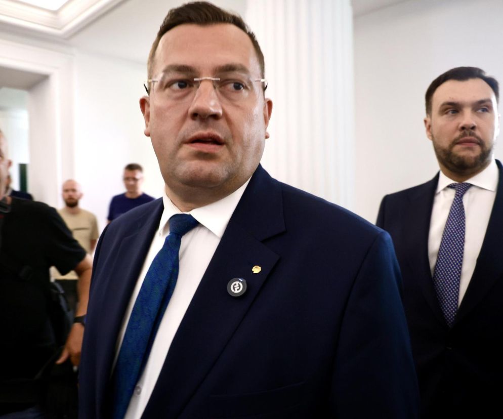 Minister Stefan Krajewski w okularach, w granatowym garniturze z niebieskim krawatem, obwieszcza historyczne wsparcie finansowe dla rolników. Na portalu Super Biznes przeczytasz o pakiecie działań i kredytach z oprocentowaniem 1%.