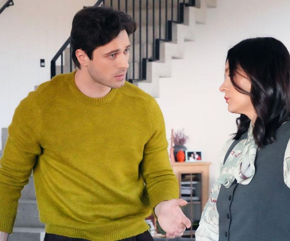 Maria Dejmek jako Natalia Zwoleńska rozmawia z Marcelem Opalińskim grającym Cezarego Rawicza, stojąc w jasnym pomieszczeniu. Cezary ubrany jest w limonkowy sweter, Natalia w jasną bluzkę ze wzorem i ciemną kamizelkę. Zdjęcie ilustruje scenę pełną obaw o konsekwencje porwania Andrzeja, którą można przeczytać na Super Seriale.