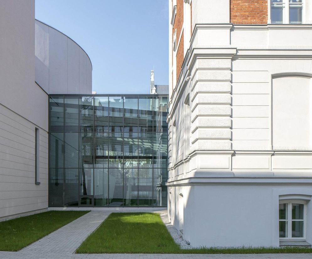 Złożenie zabytkowej i nowoczesnej architektury Zespołu Państwowych Szkół Muzycznych nr 1 w Warszawie. Widoczny szklany łącznik atrium, elewacja z cegły oraz gładka, jasna fasada nowego budynku. Więcej o tej realizacji przeczytasz na Architektura Murator Plus.