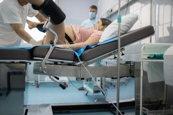 Kobieta na łóżku porodowym w otoczeniu lekarzy