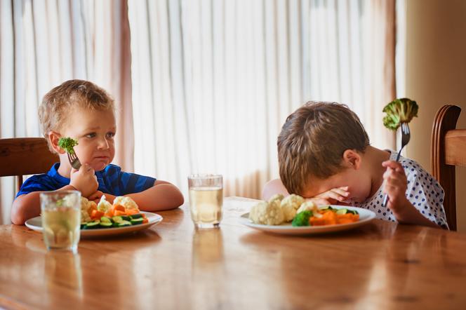 dzieci przy stole jedzące brokuły