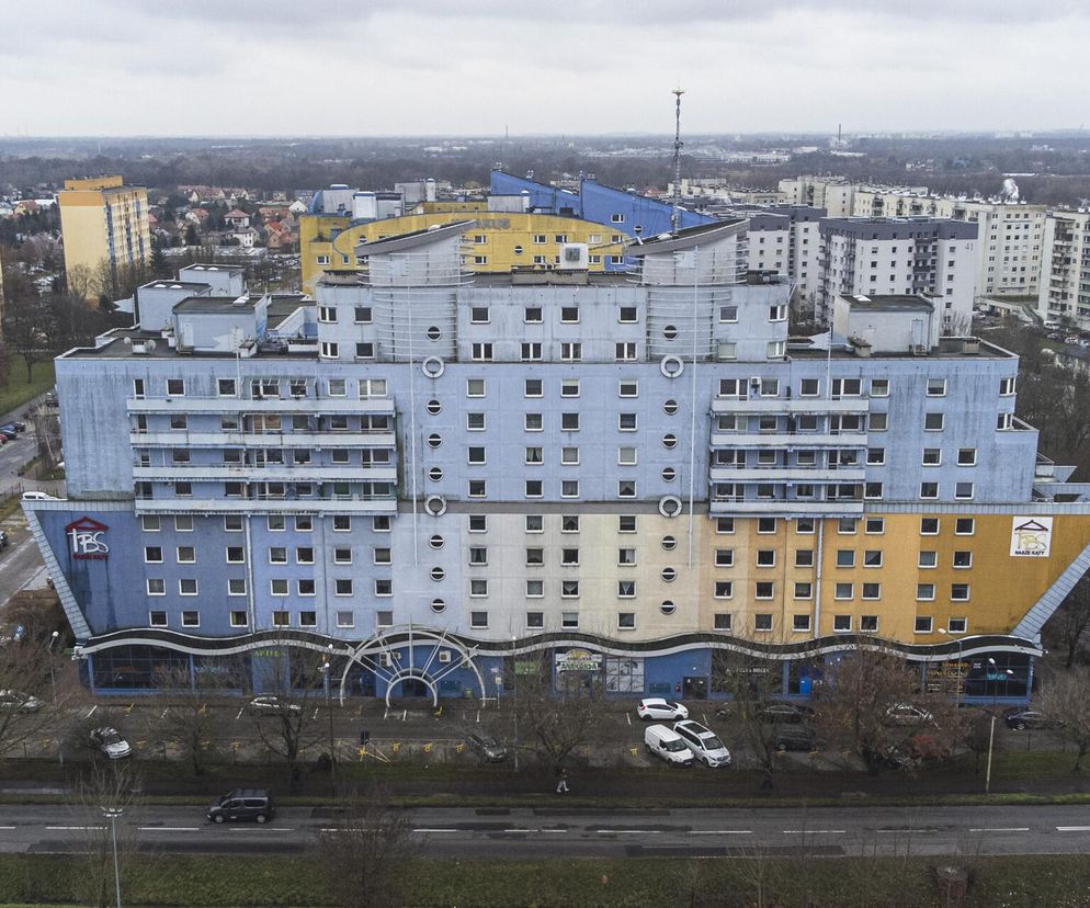 Charakterystyczny blok-statek TBS Nasze Kąty we Wrocławiu projektu Krzysztofa Skalskiego. Budynek o zaokrąglonej konstrukcji, niebiesko-żółtych elewacjach, z bulajami i elementami przypominającymi dziób i maszty, wpisuje się w nurt eksperymentów architektonicznych przełomu millenium, o czym przeczytasz na Architektura Murator Plus.