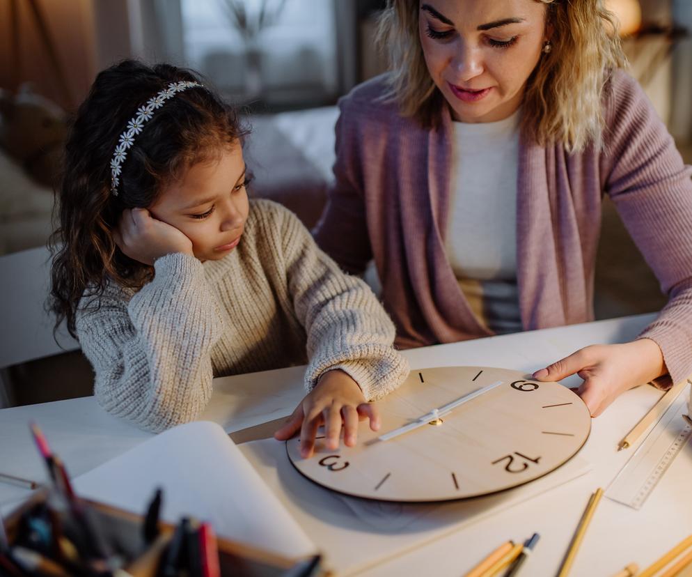 mama ucząca dziecko odczytwynia godzin na zegarze ściennym