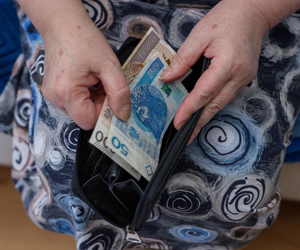 Dłonie starszej osoby wyciągające banknoty 50 zł i 200 zł z portfela, symbolizujące świadczenie wspierające dla osób z niepełnosprawnościami. Dowiedz się, kto może otrzymać nawet 4133 zł miesięcznie bez względu na dochód na portalu Poradnik Zdrowie.