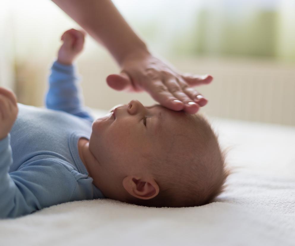 Mama dotyka czoła niemowlęcia z gorączką