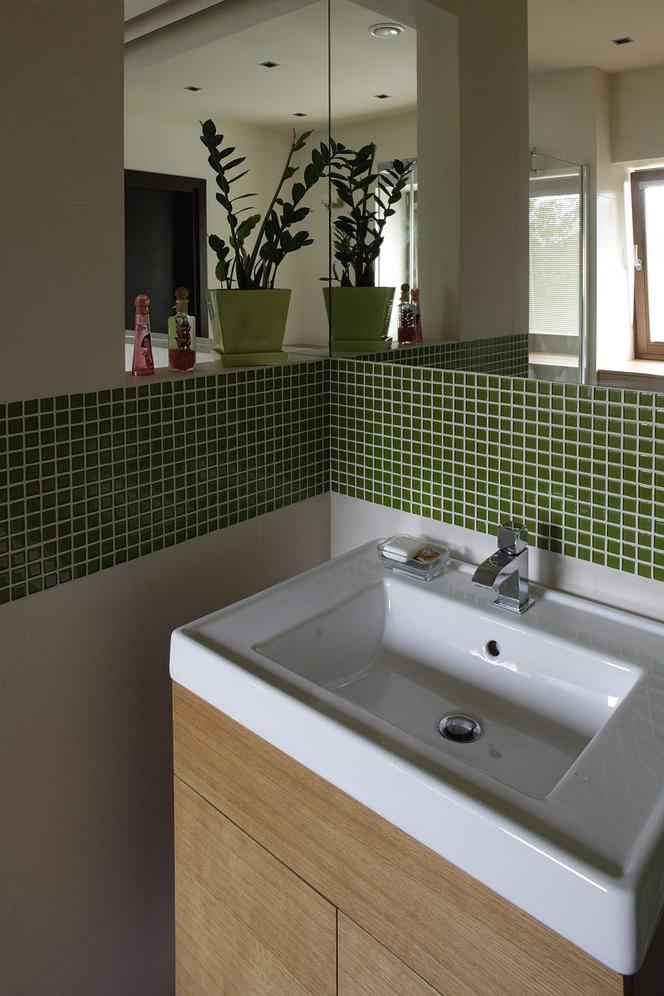 Zielona łazienka z mozaiką nad umywalką