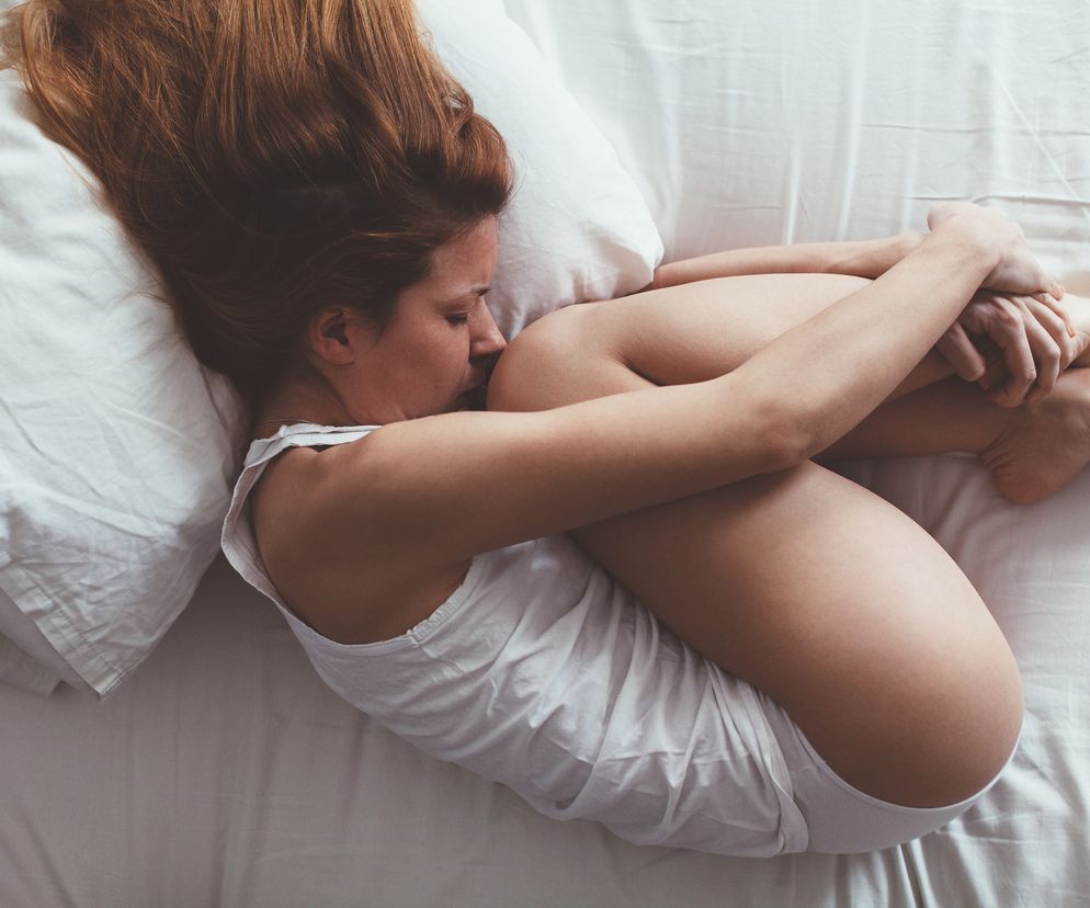 Kobieta leży zwinięta na łóżku