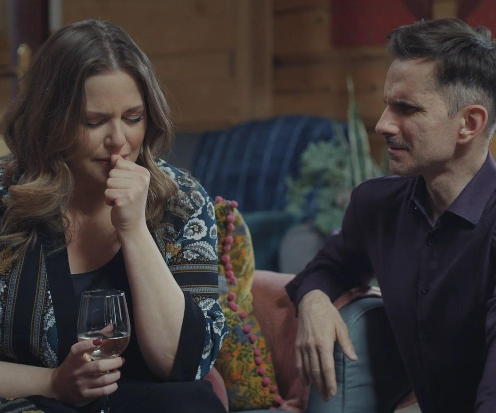 Zrozpaczona Anita (Melania Grzesiewicz) trzymająca kieliszek wina, próbuje powstrzymać łzy, podczas gdy obok siedzi Kamil (Marcin Bosak). Zdjęcie przedstawia dramatyczną konfrontację pary z serialu M jak miłość. Więcej o kryzysie w ich związku można przeczytać na Super Seriale.