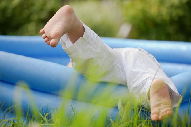 Dziecko wpadające do baseniku dmuchanego w ogrodzie