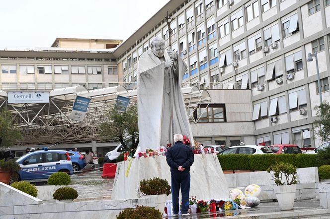 Wierni modlą się o zdrowie Franciszka przed pomnikiem Jana Pawła II. Składają kartki z życzeniami i wiązanki z białych róż