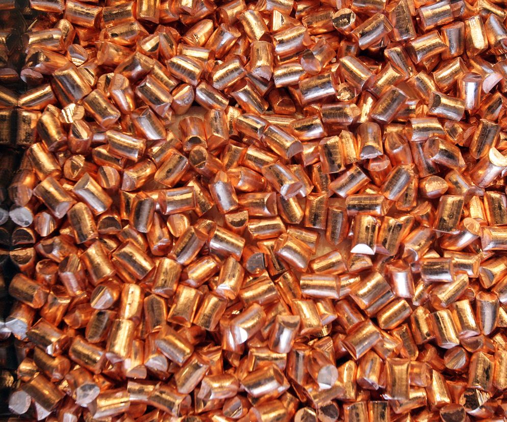 Zbiór metalicznych, cylindrycznych granulek miedzi, widocznych z góry, symbolizuje obfitość złóż i potencjał surowcowy Polski. Artykuł na Super Biznes informuje o gigantycznych zasobach miedzi w kraju.