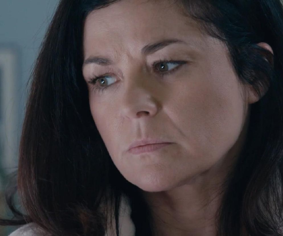 Zamyślona Kinga Zduńska (Katarzyna Cichopek) z M jak miłość z poważnym wyrazem twarzy, sprawiająca wrażenie zmartwionej lub przestraszonej. Ma ciemne włosy i patrzy w bok. Opis dramatycznej sytuacji Kingi znajdziesz na Super Seriale.