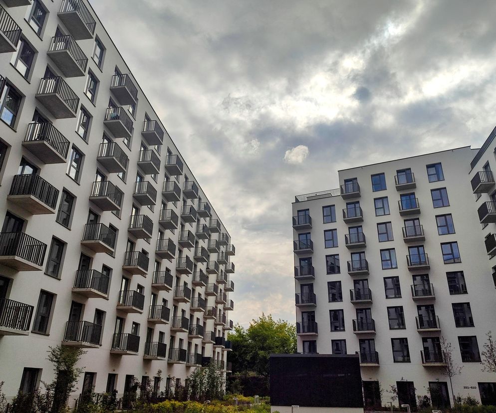 Nowoczesne białe bloki mieszkalne z rzędami balkonów na tle pochmurnego nieba w Krakowie przy ulicy Romanowicza. To kompleks, który miał być akademikiem, a będzie oferował 870 mieszkań na wynajem, o czym przeczytasz na Architektura Murator Plus.