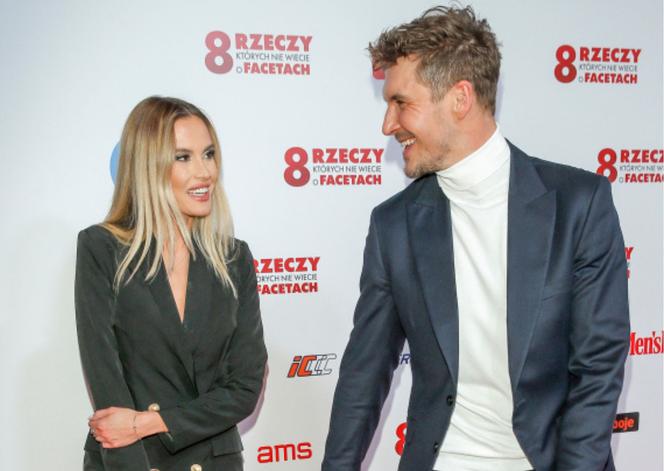 Rozpromieniony Mikołaj Roznerski czule uśmiecha się do tajemniczej blondynki na premierze filmu