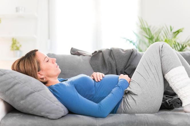 kobieta w ciąży leżąca zmęczona na kanapie