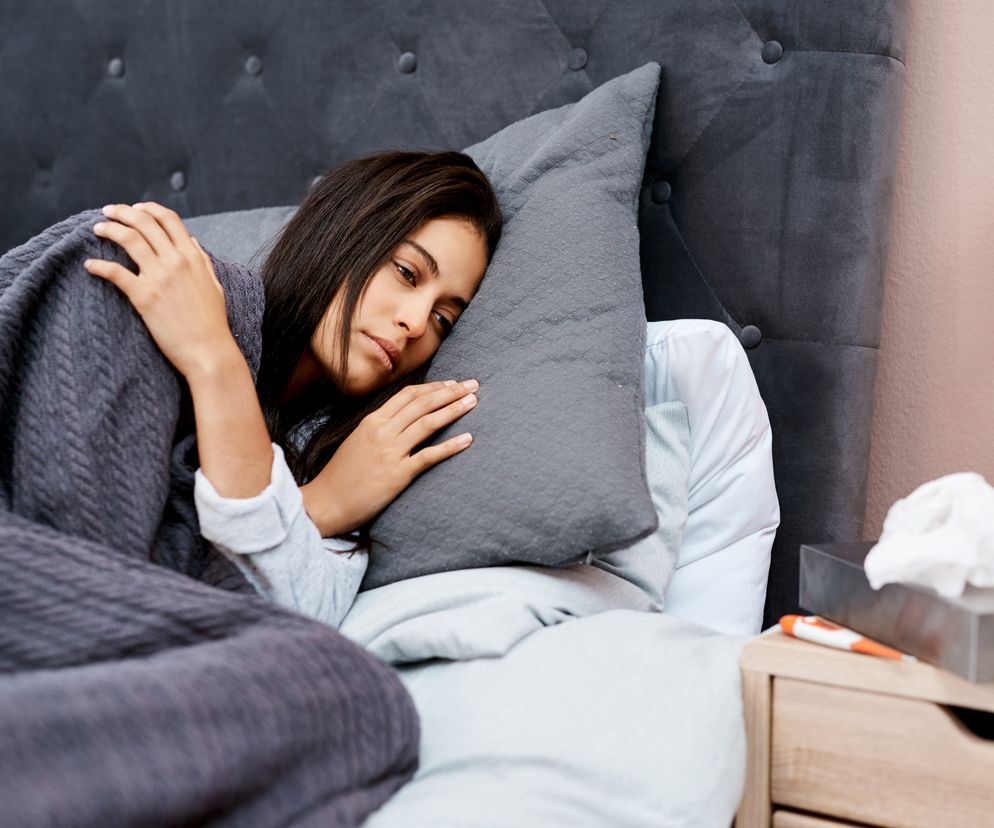 Młoda kobieta leży w łóżku z gorączką