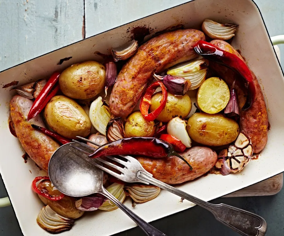 Lepkie kiełbaski pieczone na warzywach. Przepis na rewelacyjne danie z jednej blaszki