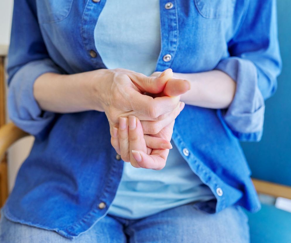 Kobieta w denimowej koszuli wykonuje test kciuka na tętniaka aorty: zgina kciuk w poprzek dłoni. Zdjęcie ilustruje prostą metodę oceny ryzyka, o której przeczytasz więcej na Poradnik Zdrowie.