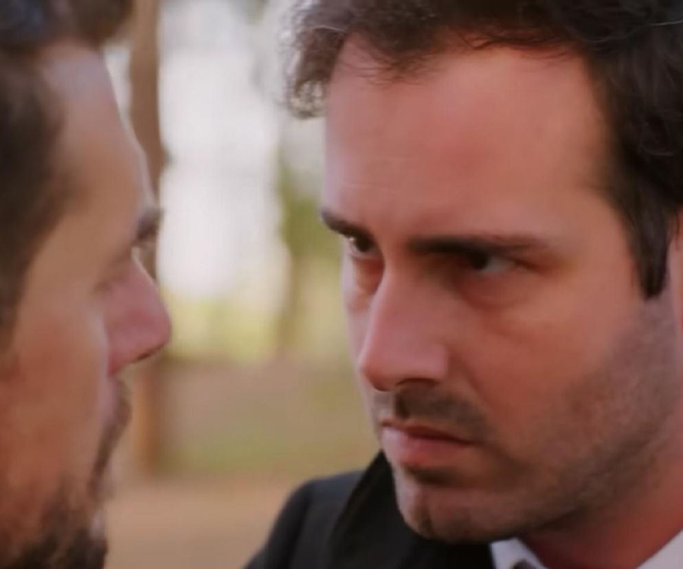 Zbliżenie na twarze dwóch mężczyzn, Kuzeya (z prawej, w białej koszuli i ciemnej marynarce) i Leventa (z lewej, z zarostem, tyłem do widza), intensywnie patrzących na siebie. Kuzey ma zacięty wyraz twarzy, co oddaje napięcie akcji z serialu „Miłość i nadzieja”, gdzie Levent zostanie okradziony. Więcej szczegółów na Super Seriale.