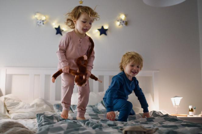 Dwoje małych dzieci skaczących po łóżku