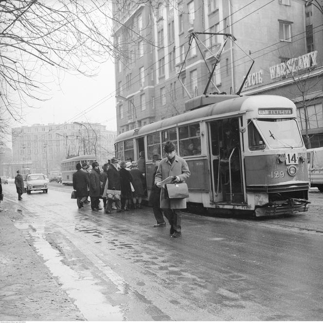  Przechodnie wsiadają do tramwaju Konstal 13N linii 14 na ul. Marszałkowskiej. Na jezdni samochód Syrena 104. W tle pl. Unii Lubelskiej