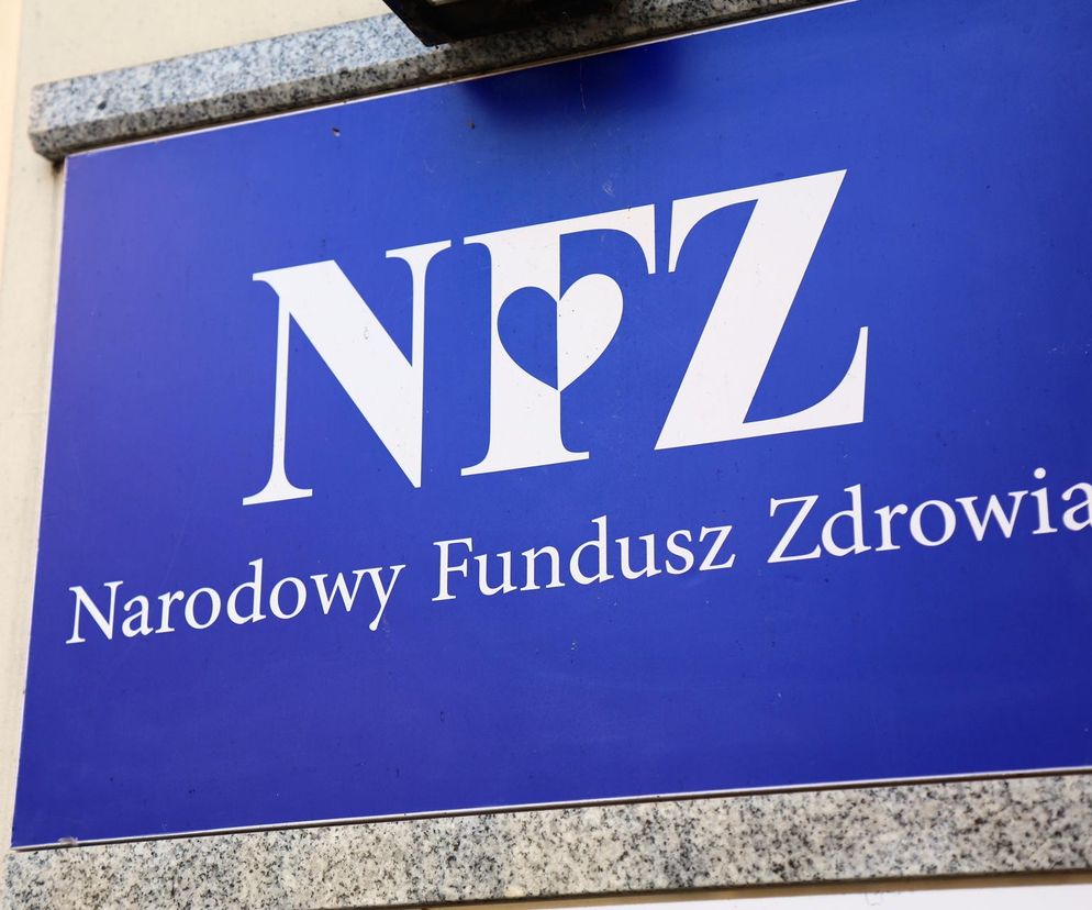 Tablica z logo NFZ, Narodowy Fundusz Zdrowia, widoczna na budynku. Symbolizuje problemy finansowania opieki zdrowotnej w Polsce, gdzie pomimo rosnących nakładów pacjenci wciąż odczuwają niedobory, o czym można przeczytać w Super Biznes.