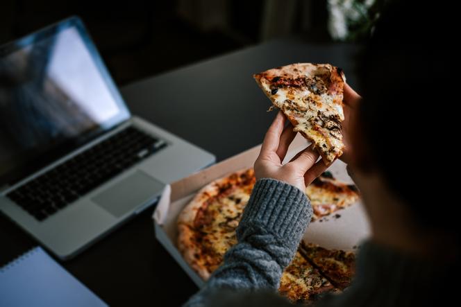 Zbliżenie na kobietę, która spożywa kawałek pizzy