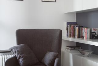 Półki na książki i fotel w aranżacji salonu
