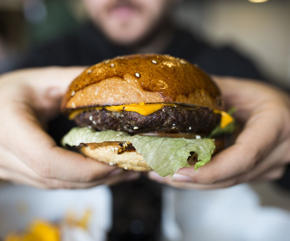 Mężczyzna spożywa burgera. 