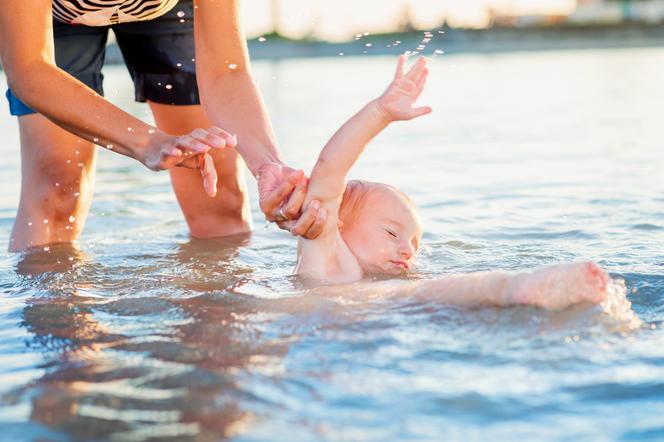 Dziecko wyciągane z wody przez matkę